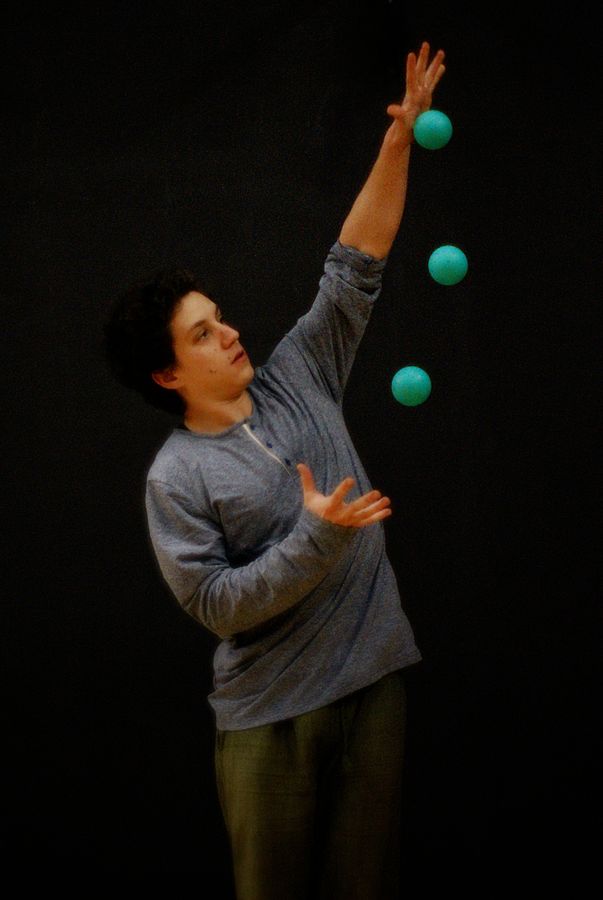 Martin pratique la jonglerie avec trois balles au plateau 4 des Subsistances. Les balles forment un arc de cercle entre ses mains.