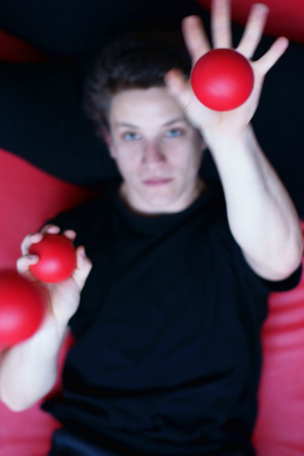 Martin pratique la jonglerie à plat dos avec des balles rouges sur un tapis du gymnase d'Overground Circus. Seule la balle la plus haute est nette.