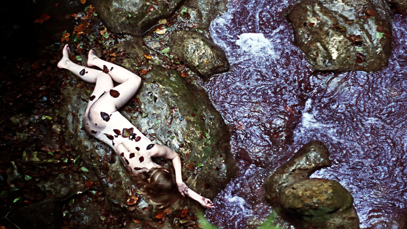 Le corps bleuté d'Hata semble avoir été abandonné sur une pierre plate de cette rivière du Buget. Des feuilles mortes sont collées sur le corps de la noyée.