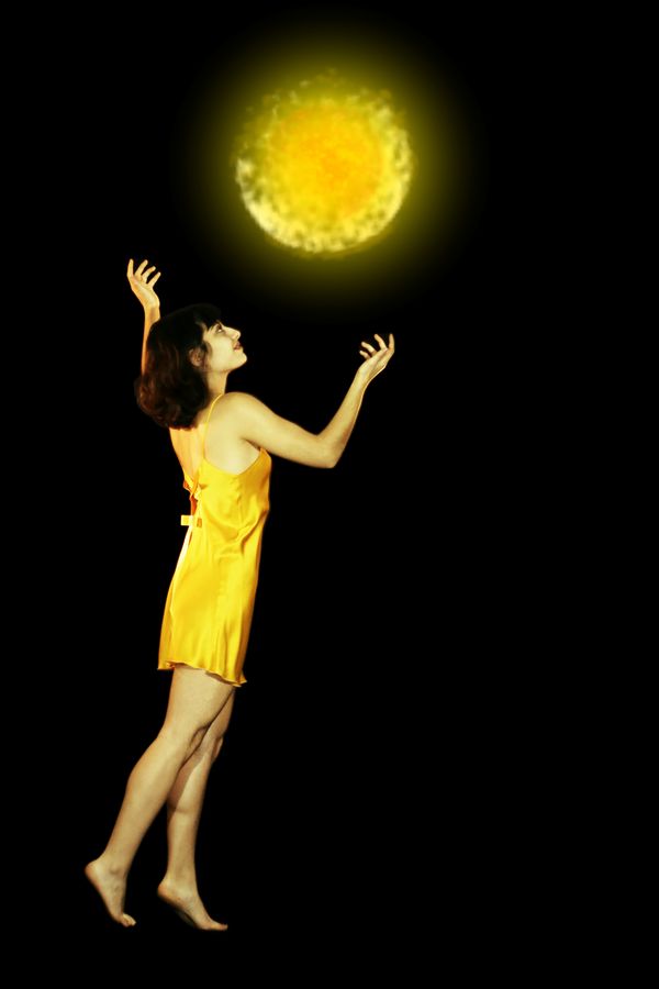 Maeva, la magicienne jaune en nuisette de soie, invoque un soleil. La mini-boule de feu flotte dans les airs et éclaire Maeva de sa puissante lumière.