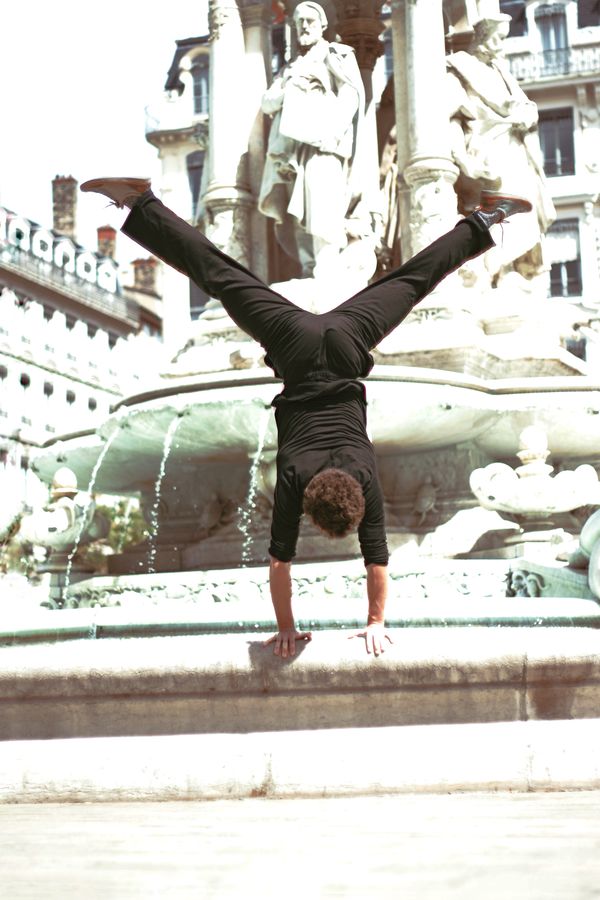 Martin est en équilibre sur le bord de la fontaine des Jacobins, à Lyon. L'image surexposée, fait ressortir le contraste entre son corps et le marbre blanc.