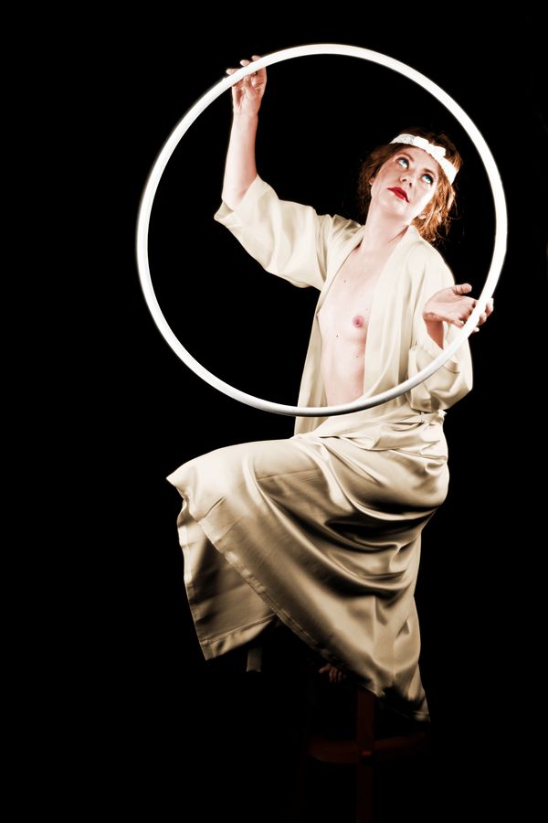 Alix-Betty pose en déshabillé de soie. Son hula-hoop lui sert de cadre et l'image est recolorisée à la manière des années 20.