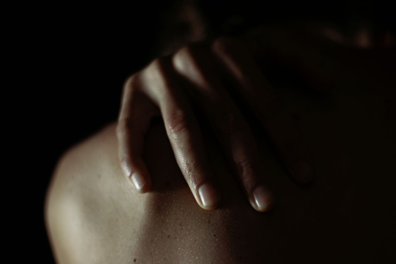 Plan rapproché des doigts de Céline qui reposent tranquillement sur son épaule. L'éclairage de studio permet de créer de jolies ombres.