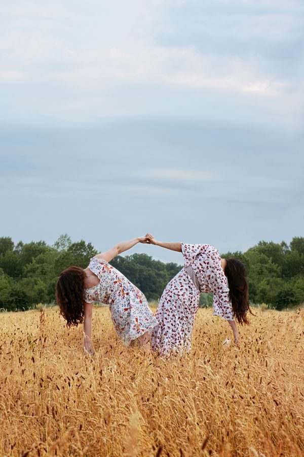 Iona et Marine, en robes à fleurs se tiennent par la main, dans un champ de blé sauvage au parc de la Feyssine à Villeurbanne.