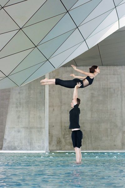 Jonas porte Mathilde en hirondelle au Musée des Confluences. Ils sont debout dans le bassin avec les pieds dans l'eau.