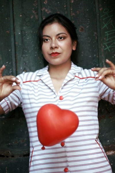 Ana porte une robe vintage à rayure de la friperie les Jupons de Paulette. Un ballon rouge en forme de cœur tombe devant elle.
